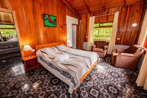 a bedroom with a bed and two chairs in it at Cabañas La Pradera in Monteverde Costa Rica