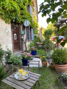 einen Garten mit einem Tisch und einer Uhr an der Seite eines Gebäudes in der Unterkunft B&B de charme La Maison des 5 Temps in Ferrette