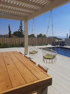 a patio with a wooden table and two swings at רוח ברמה in Bruchim Qela' Alon