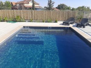a swimming pool with two chairs in a backyard at רוח ברמה in Bruchim Qela' Alon