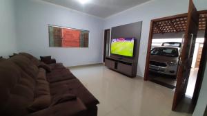 a living room with a couch and a flat screen tv at Caliandra Casa de temporada in Pirenópolis