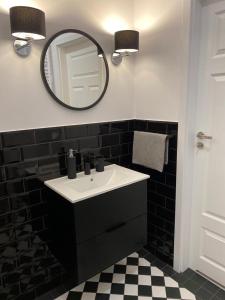 a black and white bathroom with a sink and a mirror at Apartament Platinum Park in Stargard