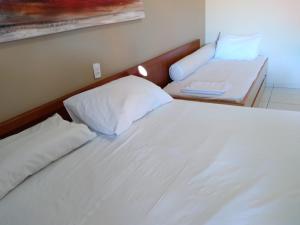 a bedroom with a white bed and a desk at Amarilis Flat Apartament in Riviera de São Lourenço +46 photos