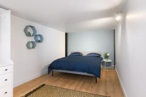 um quarto com uma cama azul e paredes brancas em Beautiful loft in a former factory in Tourcoing - Welkeys em Tourcoing