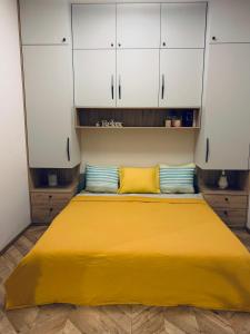 een groot geel bed in een kamer met witte kasten bij Botanical Manor Apartment in Kaunas