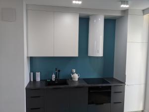 a kitchen with white cabinets and a black counter top at Śledź Gdynia - YACHT PARK in Gdynia