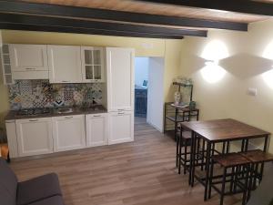 a kitchen with white cabinets and a table and chairs at Rega Holiday House in Naples