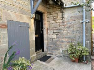 une maison en pierre avec une porte noire et quelques plantes dans l'établissement Lade Braes 3 Bed Apartment Central St Andrews, à St Andrews