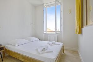 a white bedroom with a bed and a window at Charming 1br flat with sea view at the heart of Biarritz - Welkeys in Biarritz