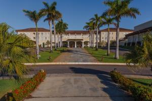 un grand bâtiment avec des palmiers et une allée. dans l'établissement Saui­pe Premium Sol All Inclusive, à Costa do Sauipe