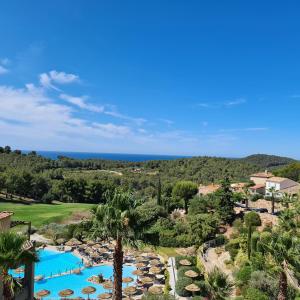 uma vista aérea de um resort com uma piscina e palmeiras em HAMEAU DES AMANDIERS - vue mer, golf et vignes em Saint-Cyr-sur-Mer