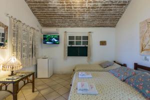 sala de estar con 2 camas y TV en Pousada Chez Nice, en Búzios