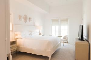 a white bedroom with a bed and a television at Oyster Bay Boutique Hotel in Pensacola