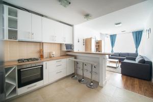 eine Küche mit weißen Schränken und ein Wohnzimmer in der Unterkunft Apartel Emerald Bay in Mamaia Nord – Năvodari
