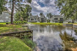 a home with a pond in front of houses at Lovely Myrtle Beach Condo 4 Mi to Boardwalk! in Myrtle Beach