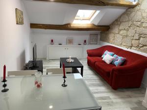 a living room with a red couch and a table at RUA NOVA APARTMENT ATICO 3º,a 200m CATEDRAL,PS 4 y NETFLIX in Santiago de Compostela