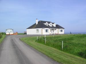 a house on the side of a dirt road at The Antlers in Lybster