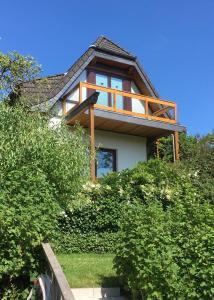 uma casa com uma varanda no topo de alguns arbustos em Ferienwohnung Smutje em Kiel
