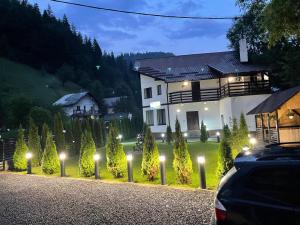 a house with lights on a driveway at night at Pensiunea Julian House in Moieciu de Jos