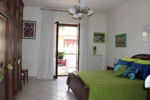 um quarto com uma cama verde e uma porta de vidro deslizante em B&B Casa Ippolito Stabiae Coast em Castellammare di Stabia