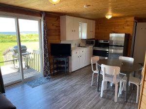 a kitchen and dining room with a table and a television at Cottages On PEI-Oceanfront in Bedeque