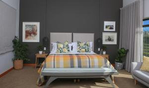 Hudson Manor - Entabeni, Knysna في كنيسنا: غرفة نوم مع سرير كبير مع وسائد ملونة
