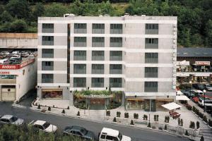 un gran edificio blanco con coches aparcados en un aparcamiento en Zenit Diplomatic, en Andorra la Vella