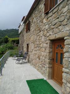 a stone building with two chairs and a wooden door at Casa da quintinha - Turismo rural in Arcos de Valdevez