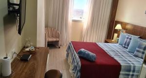 a hotel room with a large bed and a table at Lindo Flat Aconchegante no Centro de Taguatinga in Taguatinga