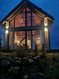 ein Haus mit großen Glasfenstern und Lichtern in der Unterkunft WIATR W KOMINIE dostęp do jeziora UBLIK in Konopki Wielkie