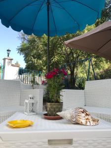 Biały stół z niebieskim parasolem na patio w obiekcie Monolocale Stella Marina w mieście Porto Palo