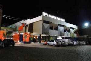 een gebouw waar 's nachts auto's voor geparkeerd staan bij Arrastão Premium Plaza in Muriaé