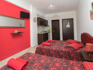 - une chambre avec 2 lits et un mur rouge dans l'établissement Villa Irida Sun, à Olympiakí Aktí