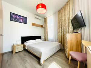 a bedroom with a bed and a flat screen tv at Apartments & Villa Georg in Odesa