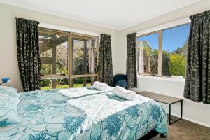 a bedroom with a blue and white bed and windows at Mercy of Lake Taupo in Taupo