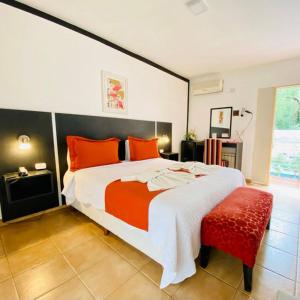 1 dormitorio con 1 cama grande con almohadas de color naranja en Hosteria Aguaribay en Mina Clavero