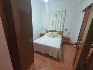 a bedroom with a white bed and a window at Los Príncipes in Palos de la Frontera