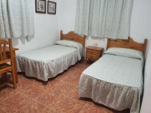 a room with two beds and a table and windows at Los Príncipes in Palos de la Frontera