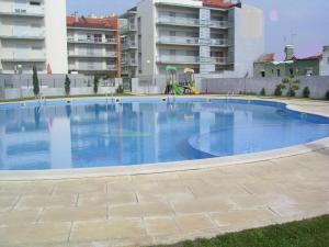 a large blue swimming pool with buildings in the background at Haven in São Martinho do Porto