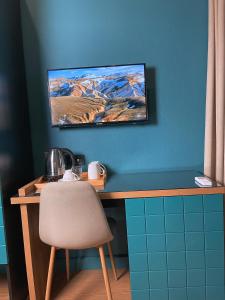 een bureau met een stoel en een televisie aan de muur bij Green Rooms in Koetaisi