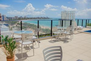 a balcony with tables and chairs and a view of the ocean at Vistamar Hotel in Maceió