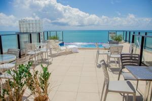 patio ze stołami i krzesłami oraz oceanem w obiekcie Vistamar Hotel w mieście Maceió