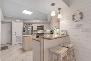 a kitchen with white walls and a counter with stools at Windward Point Unit 1004 in Orange Beach