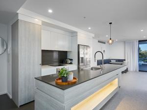 a kitchen with white cabinets and a large counter top at Boardwalk Burleigh Luxury Three Bedroom Apartment in Gold Coast
