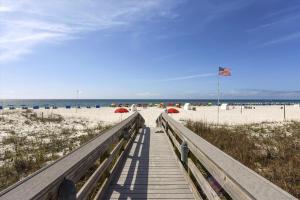a wooden boardwalk leading to the beach with umbrellas at Windward Point Unit 1004 in Orange Beach