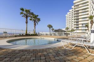 a pool with a bench and palm trees and a building at Windward Point Unit 1004 in Orange Beach