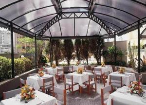 Condomínio Max Savassi Superior apto 1502 في بيلو هوريزونتي: مطعم بطاولات بيضاء وكراسي عليها ورد