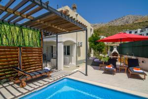un patio con piscina y sombrilla roja en Arky, en Podstrana