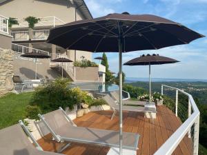 een patio met 2 stoelen en een parasol bij La cornice sul Garda - Your Home in Villanuova sul clisi