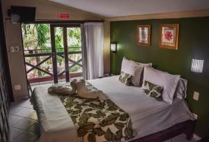 a bedroom with a bed with green walls and a window at Pousada Recanto da Coruja in Porto De Galinhas